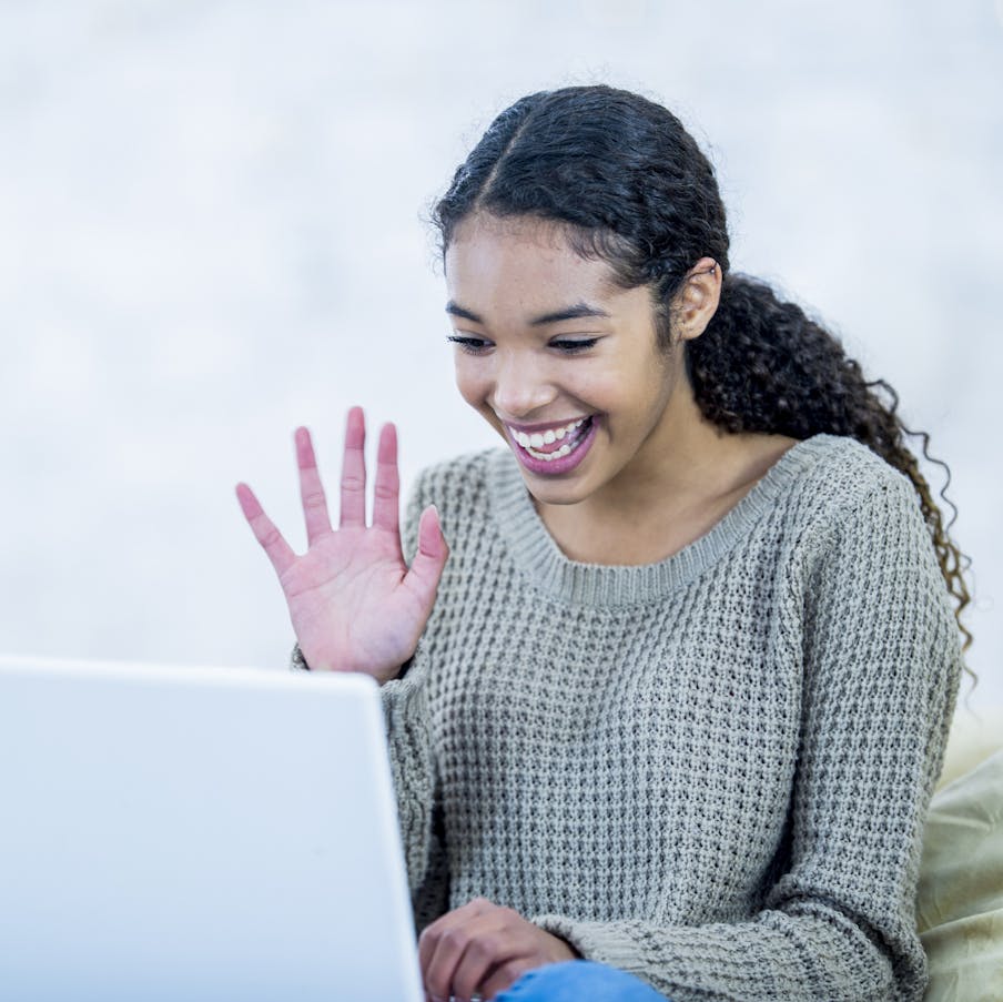 Happy woman waving at friend on computer