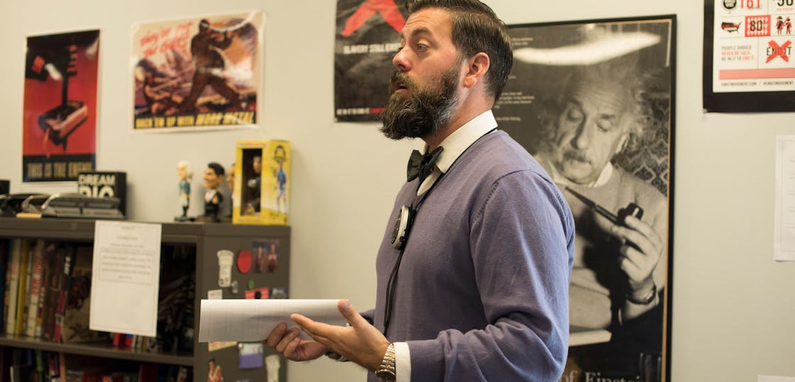 Teacher giving a lecture with a paper in his hand.