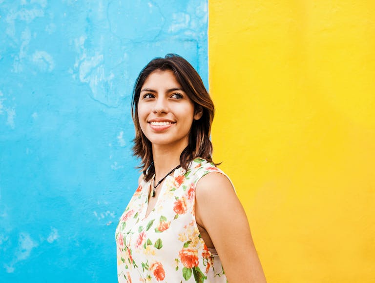  Woman smiling in front of artistic wall. 